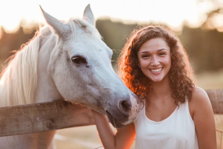 Young girl smiling next to a horse